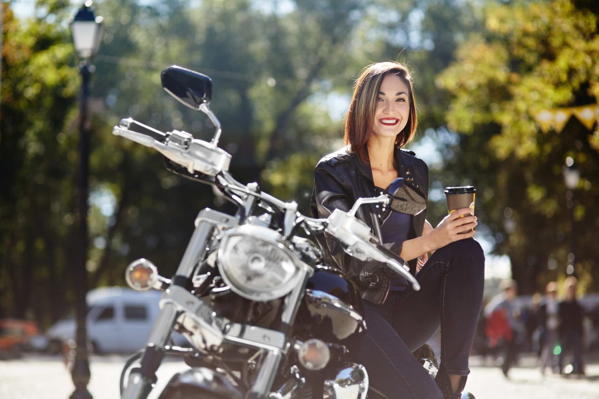 Mulher sorri e segura um capuccino sentada em sua moto adquirida pelo consórcio de motos